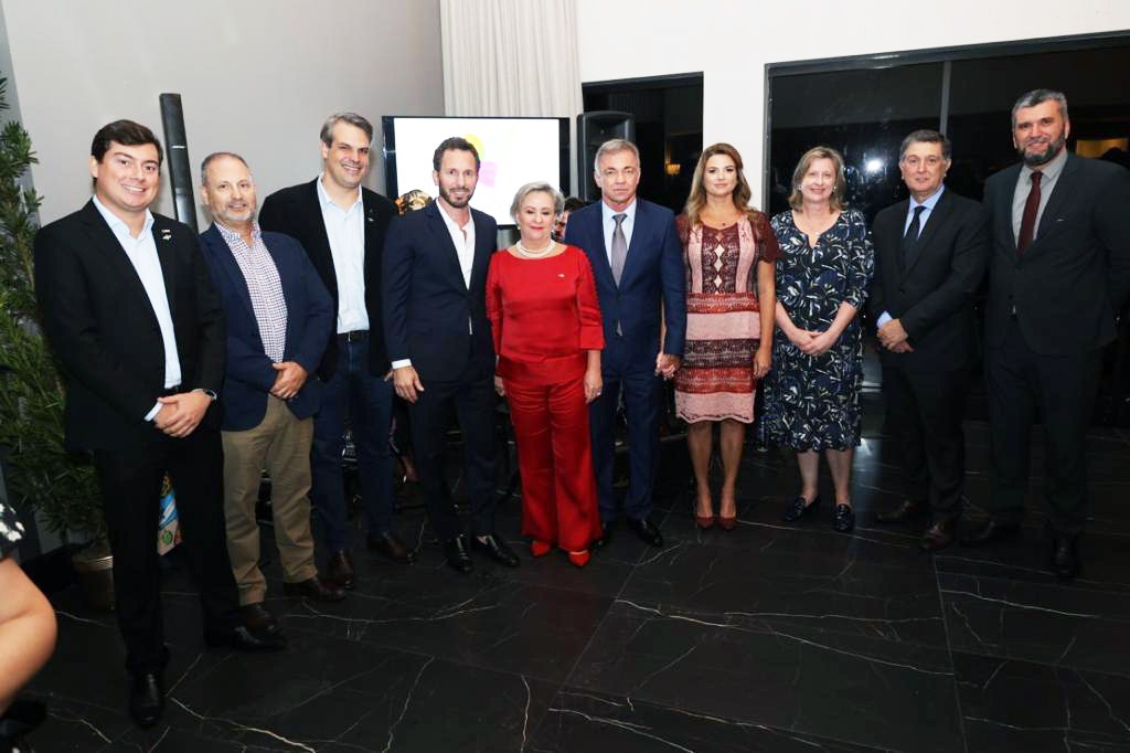 Foto colorida com cinco homens de ternos escuros e três mulheres